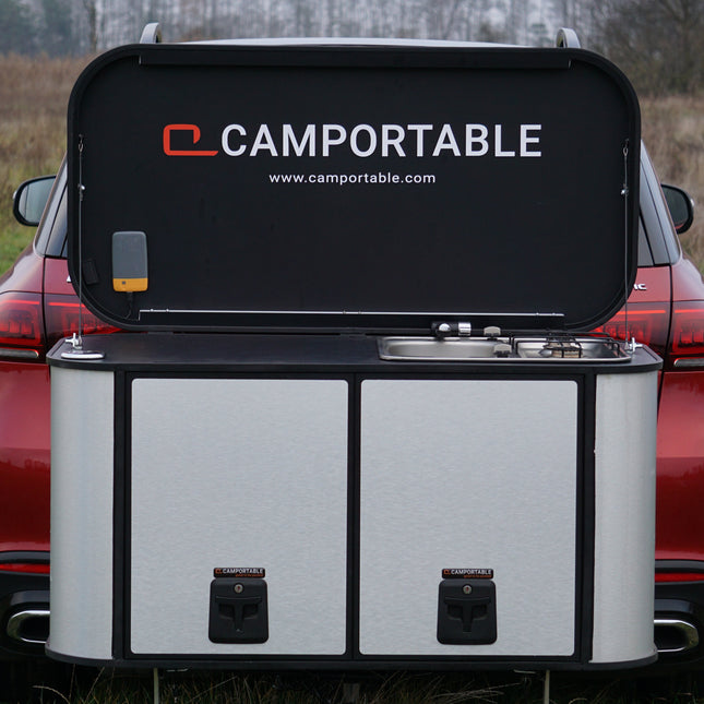 Camportable camping kitchen hitch mounted on a red car in an outdoor setting