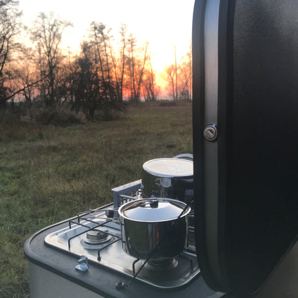 Camportable kitchen side view with sunset reflection on a grassy field